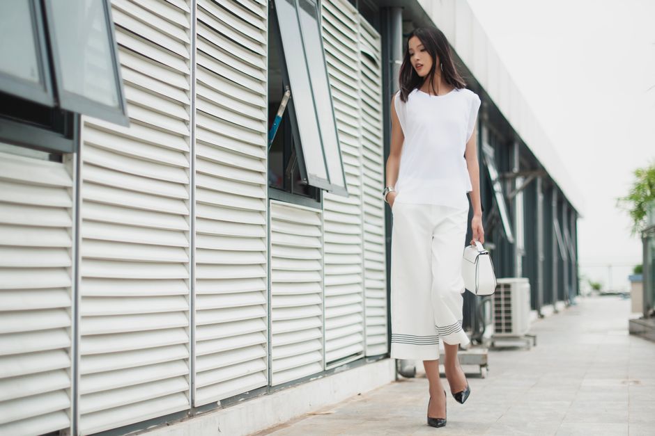 Woman wearing a simple, elegant neutral-toned outfit, walking purposefully in an urban setting, embodying quiet luxury style.