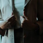 A young professional woman wearing a beige blazer and white blouse, looking composed in a modern office setting, embodying premium-looking affordable workwear.