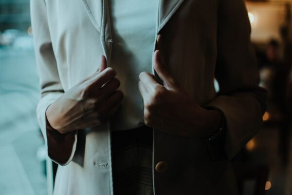 A woman in a light grey soft-shouldered blazer and wide-leg trousers, looking professional in a modern office setting.