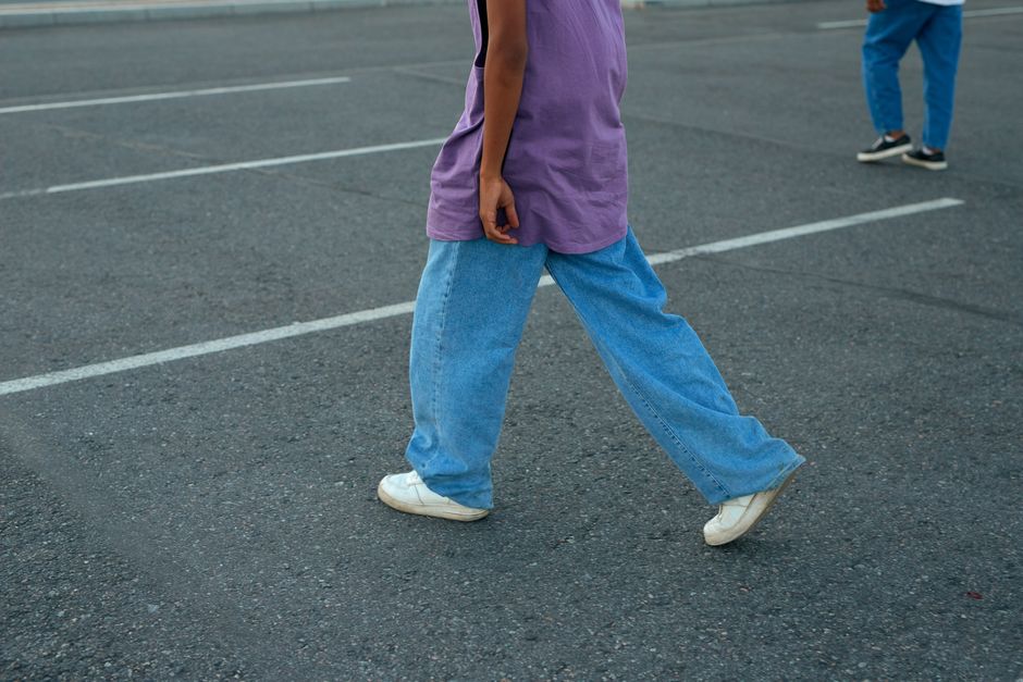 A stylish woman walking confidently down a busy European city street, wearing chic wide-leg denim jeans and a fitted top.