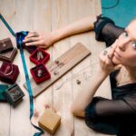 A woman thoughtfully selecting a delicate necklace from her minimalist jewelry collection, laid out on a soft fabric.