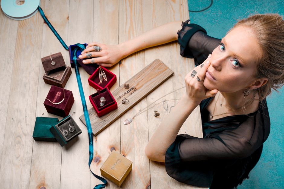 A woman thoughtfully selecting a delicate necklace from her minimalist jewelry collection, laid out on a soft fabric.