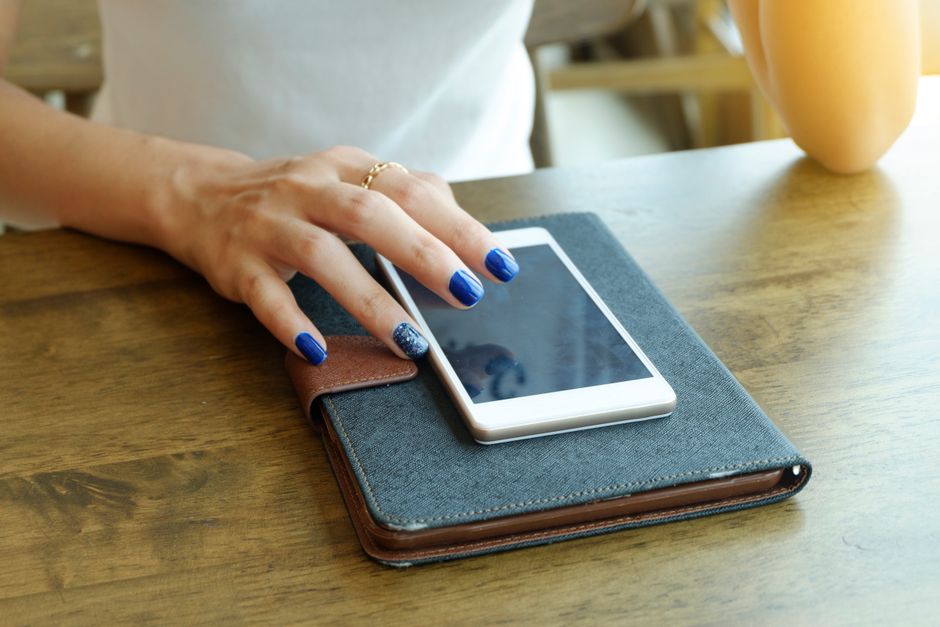 A student in a brightly lit room meticulously reviewing files and photos on her smartphone, clearing unnecessary items.