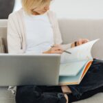 A remote worker taking a break to read a book on a comfortable sofa, laptop nearby, demonstrating how to fit reading into a busy schedule.