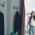 A woman in a brightly lit denim store trying on a pair of well-fitting straight-leg jeans, looking in a mirror.