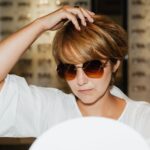 A woman trying on different pairs of sunglasses in a modern eyewear store, looking into a mirror.