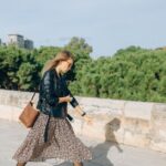 A woman walking confidently on a busy city street in Europe, wearing a practical yet stylish crossbody bag, blending in with the urban environment.