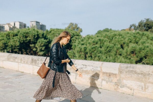 A woman walking confidently on a busy city street in Europe, wearing a practical yet stylish crossbody bag, blending in with the urban environment.