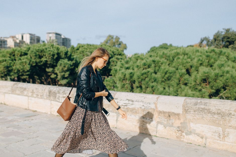 A woman walking confidently on a busy city street in Europe, wearing a practical yet stylish crossbody bag, blending in with the urban environment.