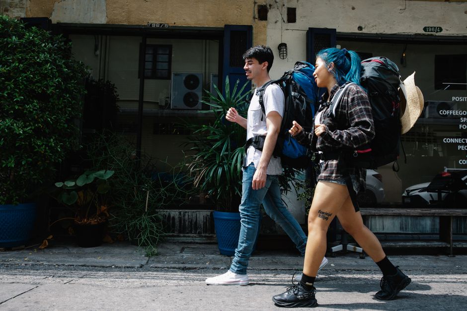 A digital nomad, a woman with a large travel backpack, walking through a bustling European city street, demonstrating ease of mobility.