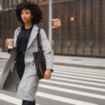A young professional woman in a light, flowing summer work outfit walks confidently down a sunny city street, showcasing a comfortable yet chic summer work wardrobe for hot cities.