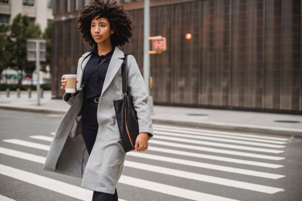 A young professional woman in a light, flowing summer work outfit walks confidently down a sunny city street, showcasing a comfortable yet chic summer work wardrobe for hot cities.