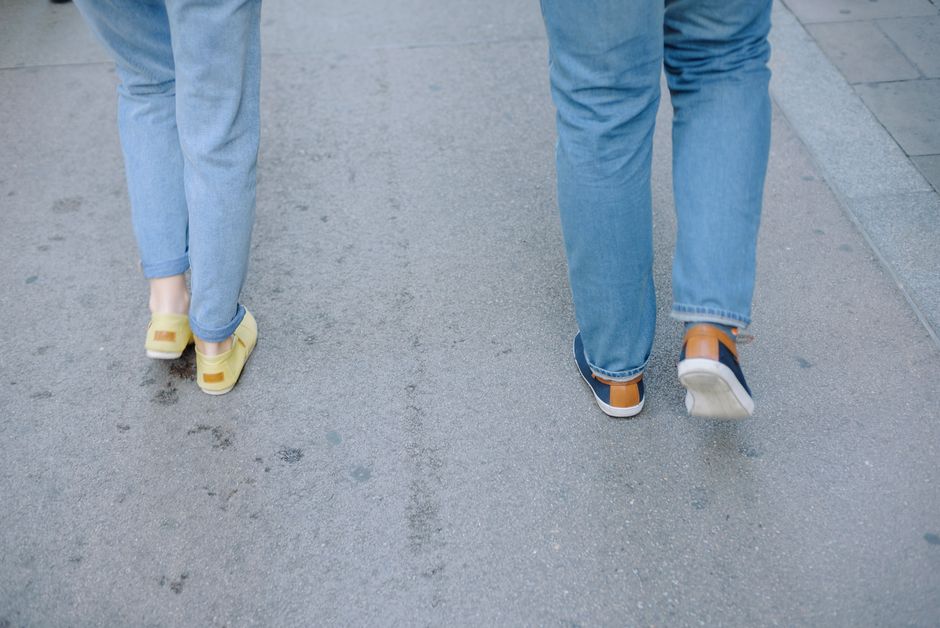A woman confidently walking down a cobblestone street in a European city, wearing comfortable yet stylish sneakers, embodying practical travel footwear choices.