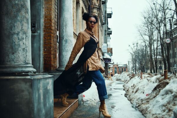 A professional woman elegantly layered in a trench coat and scarf, walking through a European city street, demonstrating versatile urban style.