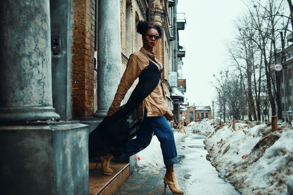 A professional woman elegantly layered in a trench coat and scarf, walking through a European city street, demonstrating versatile urban style.