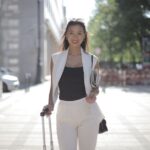 Woman in a stylish, wrinkle-resistant blazer and trousers walking briskly through a European city street, looking composed.