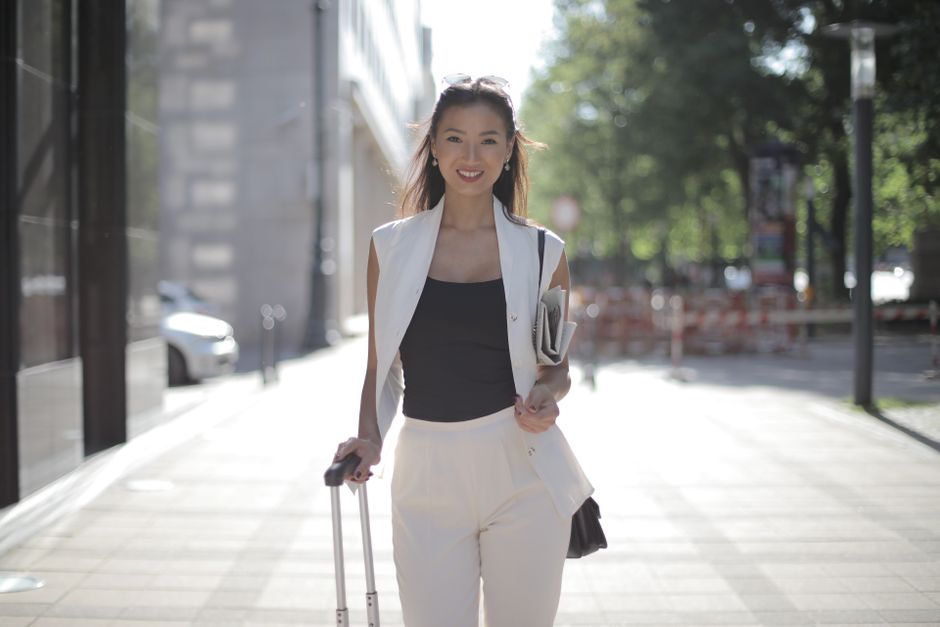 Woman in a stylish, wrinkle-resistant blazer and trousers walking briskly through a European city street, looking composed.