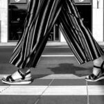 A woman wearing stylish black wide-leg pants, a fitted top, and a blazer, walking confidently in a modern city setting.