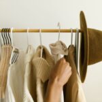 A woman smiling while looking at a rack of clothes organized by a minimalist color palette.