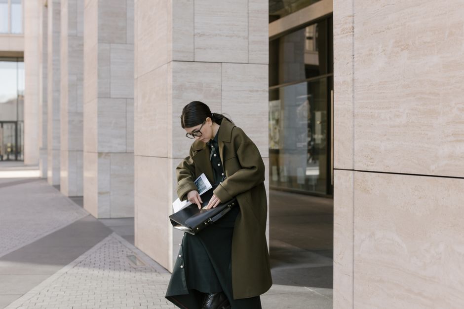 Stylish woman walking down a city street in tailored trousers, a smart blouse, and a blazer, illustrating a work outfit for hybrid jobs in an urban setting.