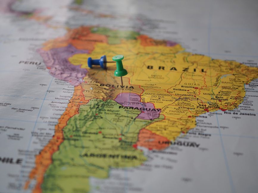 A globe highlighted with distinct pins on Europe, North America, and South America, symbolizing international travel destinations.