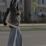 A young woman in a city street, dressed casually, walking purposefully with a reusable tote bag, illustrating an efficient urban errand trip.