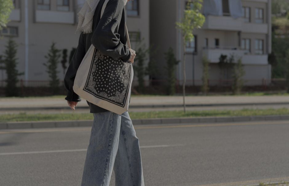 A young woman in a city street, dressed casually, walking purposefully with a reusable tote bag, illustrating an efficient urban errand trip.