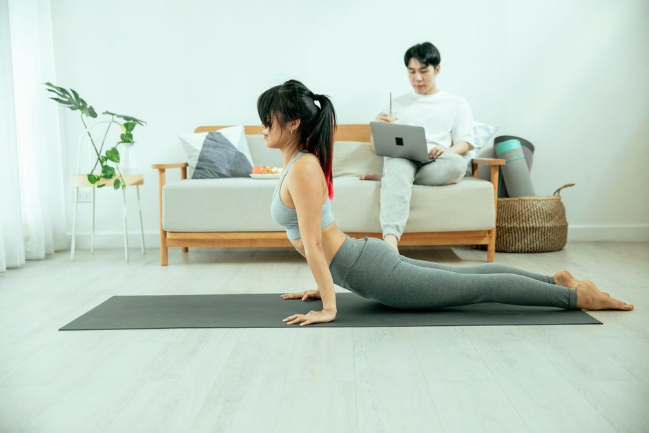 A person performing a gentle yoga pose on a mat in their brightly lit home office, emphasizing work-life balance and self-care.