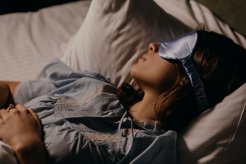 A person with an eye mask and neck pillow sleeping comfortably in a plane seat during a long-haul flight, representing frequent travel.